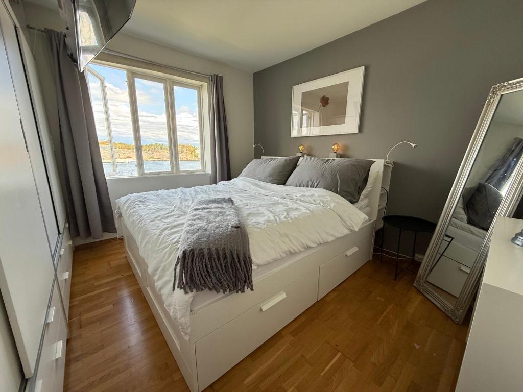 a bedroom with a bed with a mirror and a window at Bolig i sjøkanten in Arendal