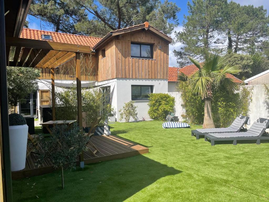 un cortile con una casa e un prato di Maison 4 chbs avec jacuzzi, au pied de la piste cyclable a Lacanau-Océan