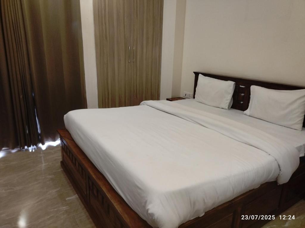 a bedroom with a large bed with white sheets and pillows at Hotel Supreme in Gurgaon