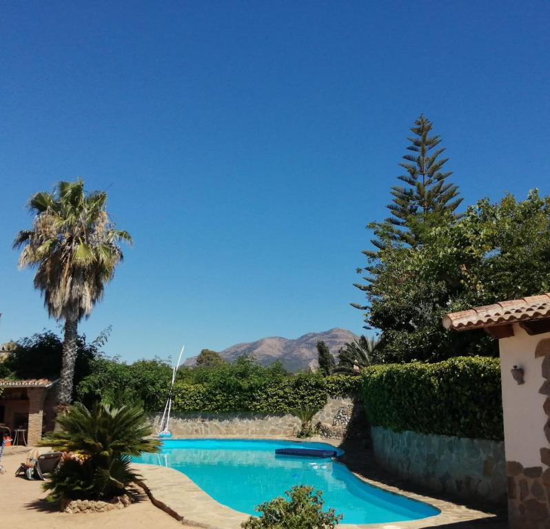 a swimming pool with a palm tree and mountains in the background at Casa Renacimiento in Coín