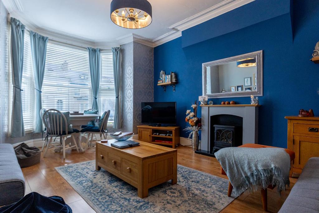 a living room with blue walls and a table and a couch at ORME RISE - Beautiful first floor apartment in Llandudno
