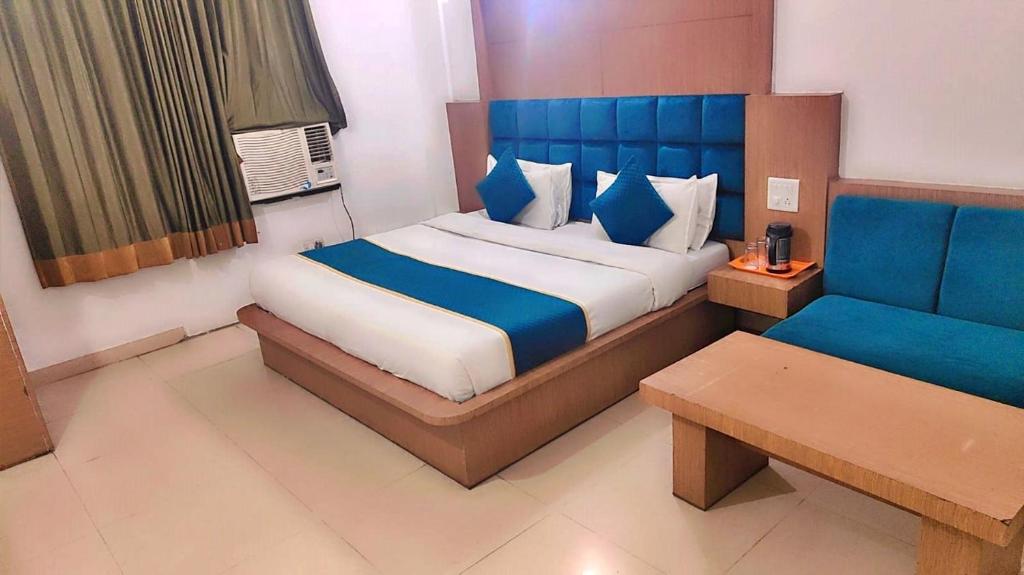 a bedroom with a large bed and a blue couch at Raa Hotel Katra in Katra