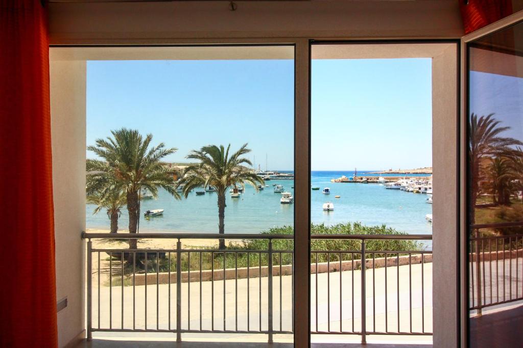 a room with a view of the beach from a window at Family Suite Porto Vecchio in Lampedusa