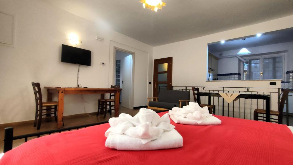 una camera con un letto rosso e asciugamani di 4 minuti da San Carlo Acutis, 8 ospiti, 140 mq, ALL'OMBRA DI SANTA CHIARA, Piano Terra 2 Ingressi 3 Camere 2 Bagni, Idromassaggio, Perfetto - La nostra Forza è PRESENZA LIVE 24-7, MyAssisiSuite, più di un semplice Appartamento - MÓWIMY PO POLSKU ad Assisi