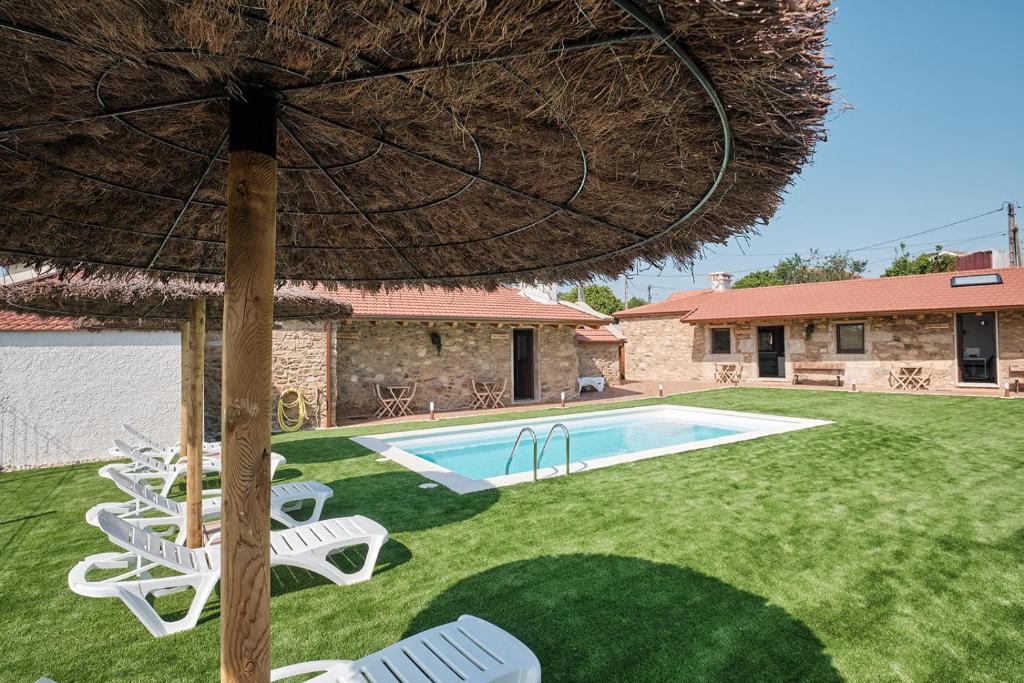 a yard with chairs and an umbrella and a swimming pool at As casiñas da Figueira by Serendipia Turismo in Pobra do Caramiñal