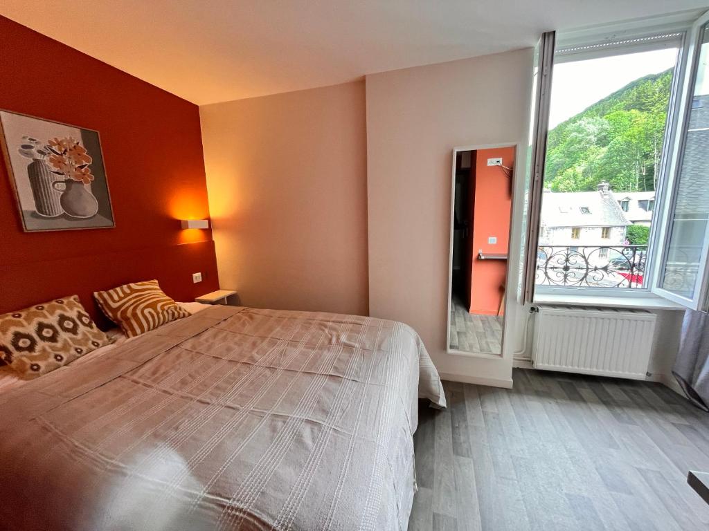 une chambre avec un grand lit et une grande fenêtre dans l'établissement Villa Le Régis, des moments simples et vrais, à Le Mont-Dore