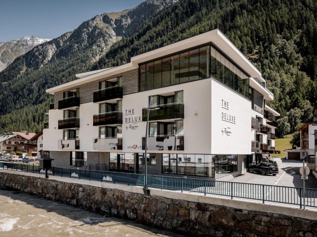 a large white building next to a river at The Deluxe by Regina in Sölden