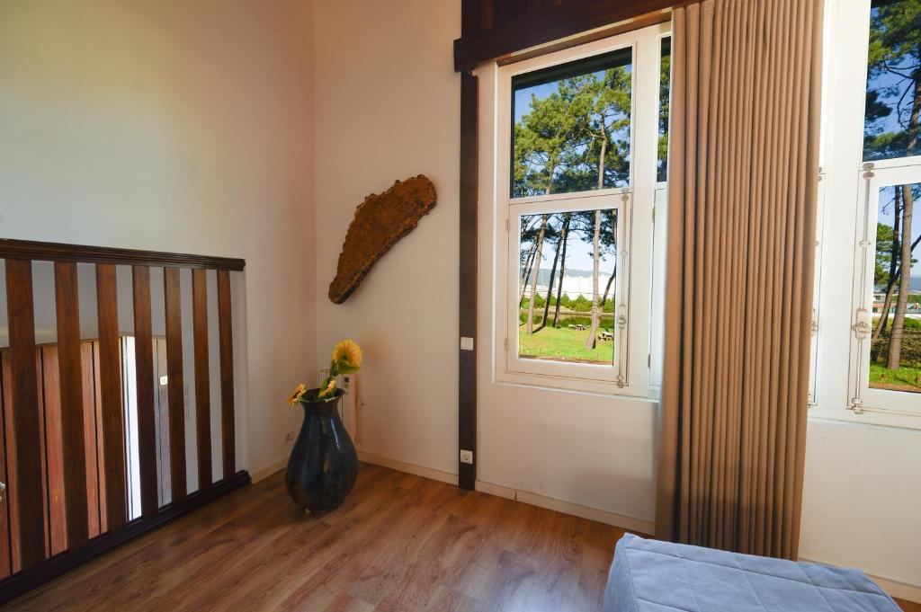 a room with a vase of flowers and a window at Cabedelo Houses - Regina Hotel Group in Darque