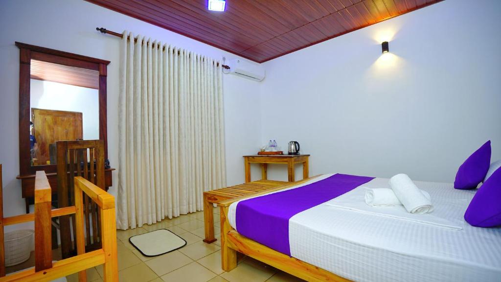 a bedroom with a bed and a mirror in it at Temple Entrance Villa in Dambulla