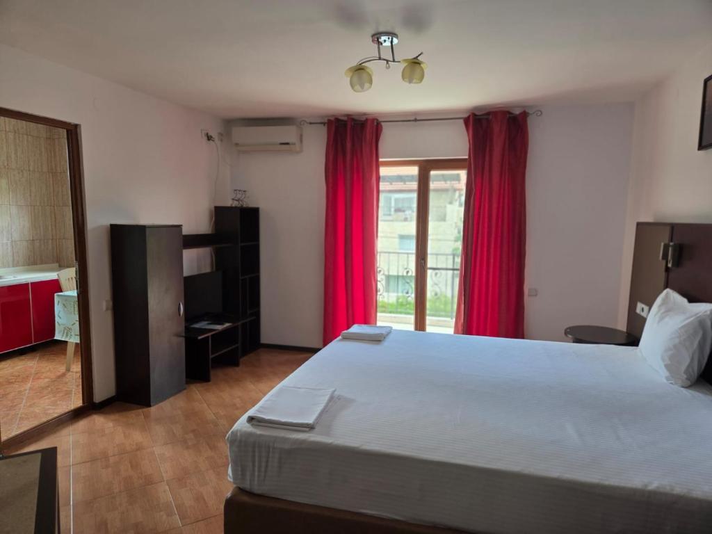 a bedroom with a large bed with red curtains at Vila Silvia in Eforie Sud