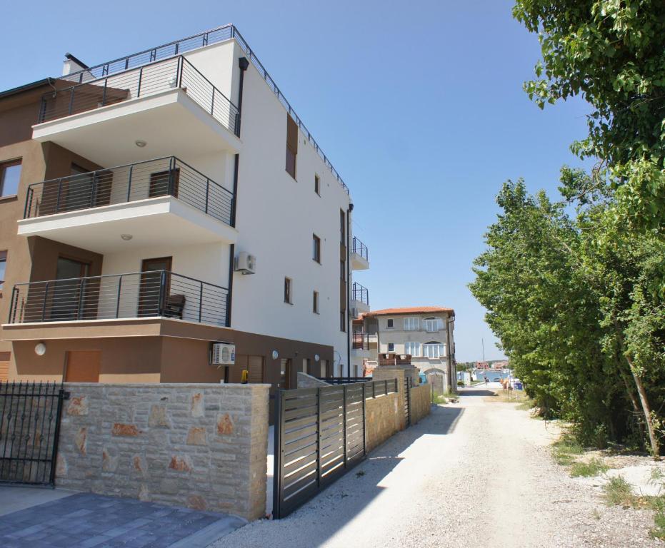 an apartment building with a fence and a dirt road at Spacious apartment sleeps 4 by the beach in Medulin