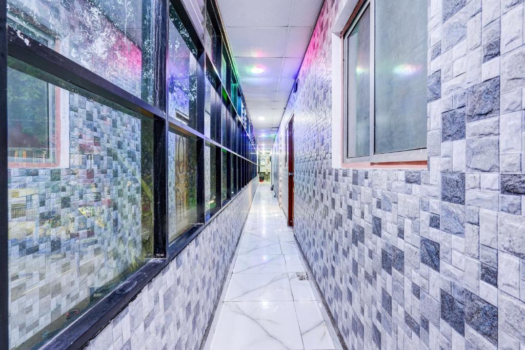 チェンナイにあるHotel O MIZPAH INNの建物内のタイル張りの壁と窓のある廊下