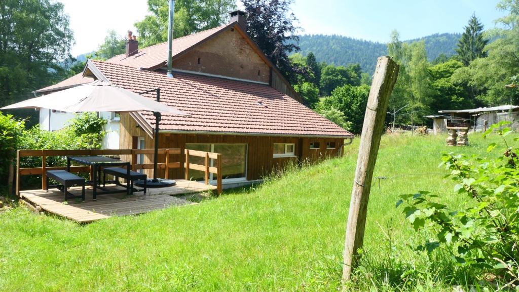 a house with a deck with a table and an umbrella at Gîte tout confort Les Champs de la Goutte à Moussey, au calme au cœur des Vosges in Moussey