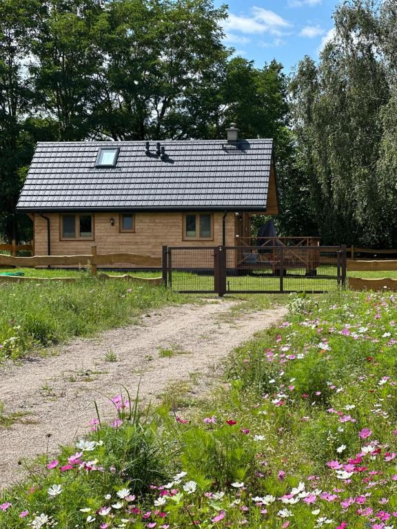 a wooden cabin with a fence and a field of flowers at Hygge z kominkiem i sauna Piasek Cedynia Chojna in Piasek