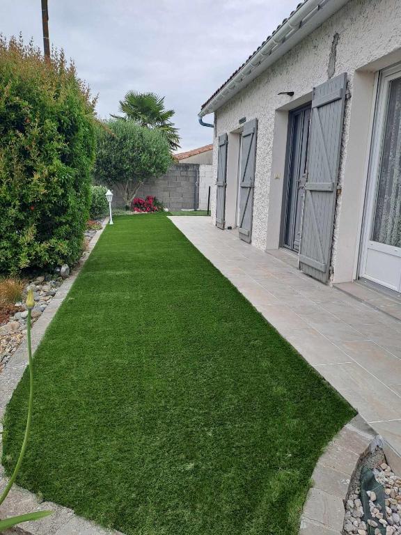 une cour avec de l'herbe verte à côté d'une maison dans l'établissement Au Coeur du Bocage Vendéen, à Chantonnay