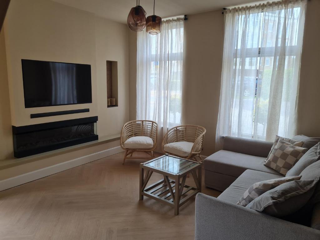 een woonkamer met een bank en een tv bij Tussen poort en toren in Sneek