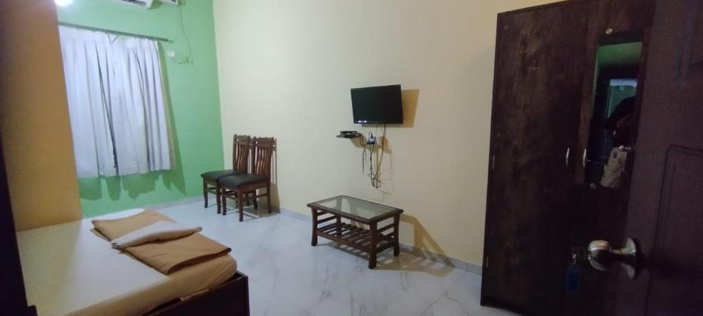 a room with a bed and two chairs and a tv at Alfina Guest House in Madgaon