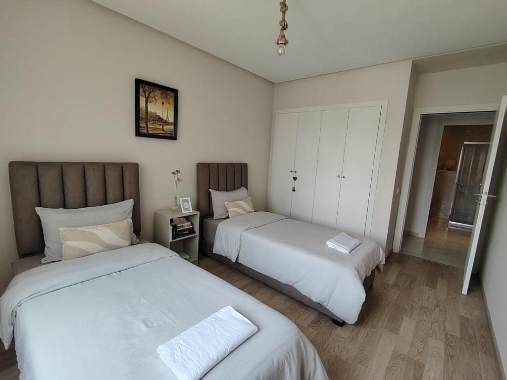a bedroom with two beds and a mirror at Chambre très propre avec salle de bain privée - 5 min airport casablanca in Nouaseur