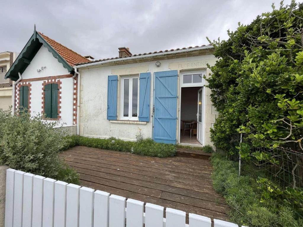 une maison blanche avec des portes bleues et une clôture dans l'établissement Charmante villa T4 face mer, proche plages et commerces, idéale familles - FR-1-324-542, à Saint-Hilaire-de-Riez