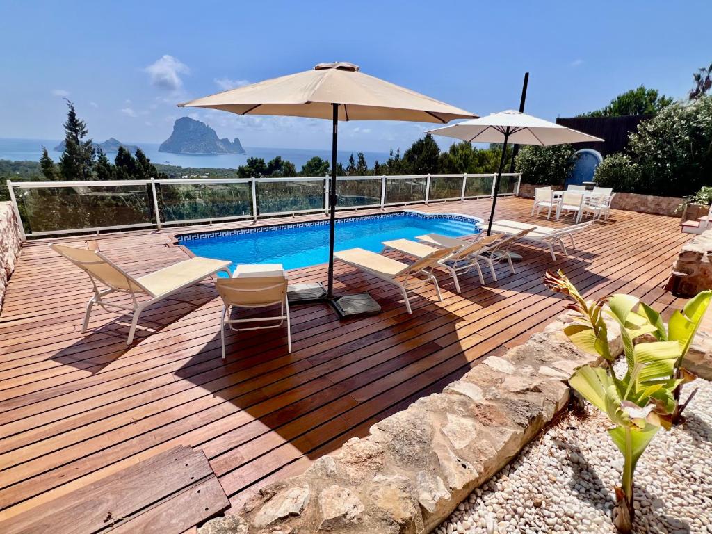 una terrazza in legno con sedie e ombrelloni accanto alla piscina di Casa Panorama a Illes Balears