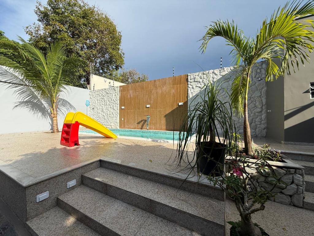 a pool with a slide and palm trees next to a building at Nossa Casa de férias em Alter do Chão in Alter do Chao