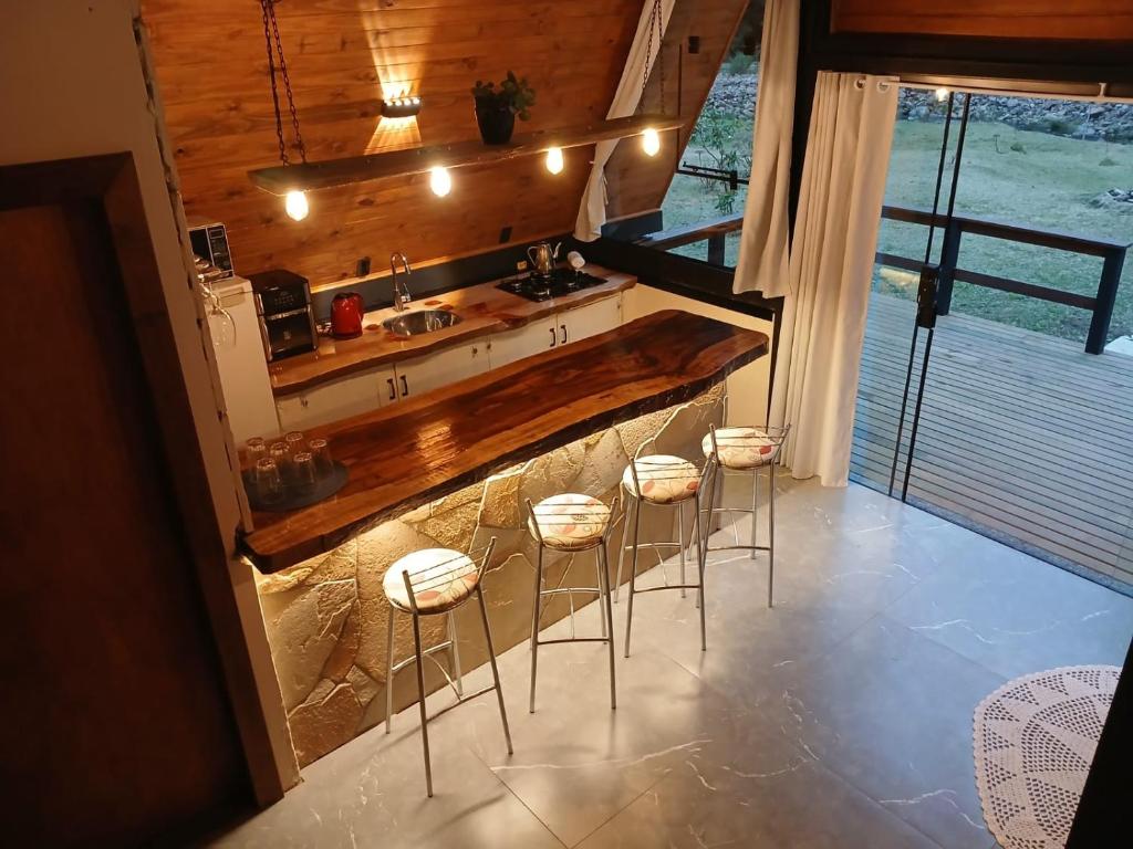 a kitchen with a counter and stools at a sink at Bendito Vale Hospedaria in Urubici