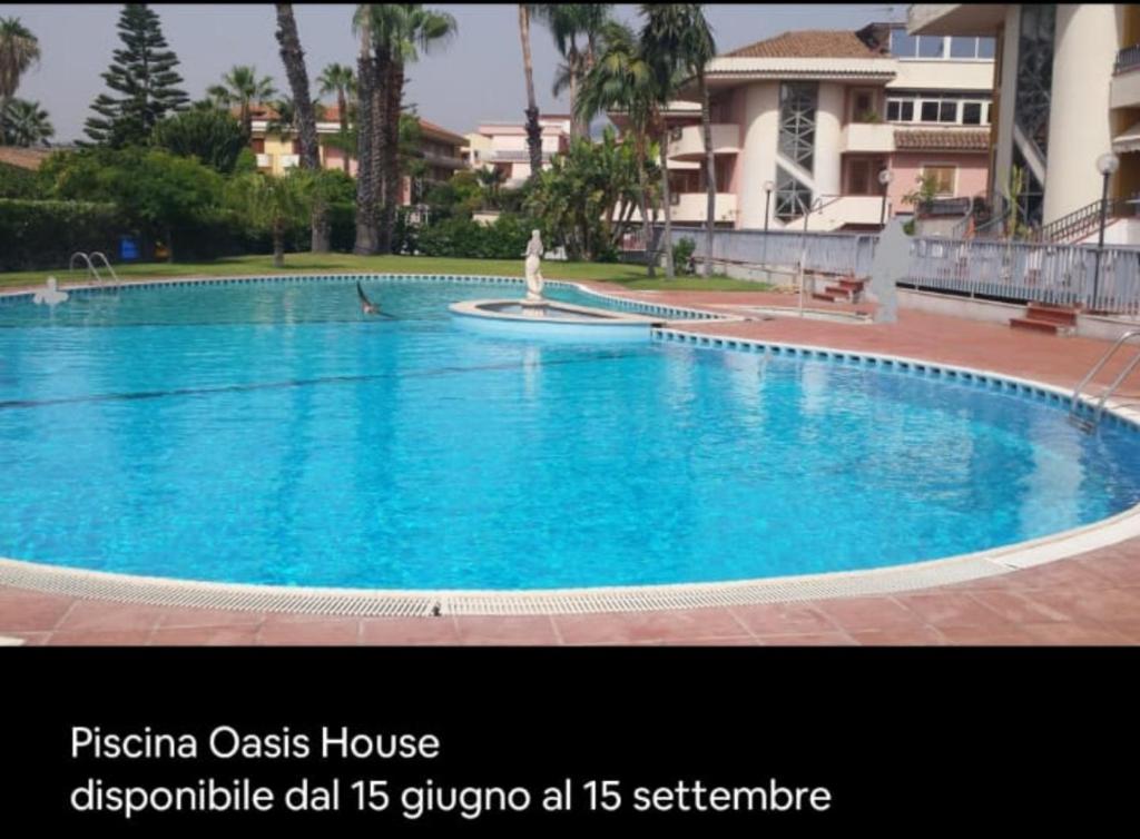 a large blue swimming pool in front of a building at Oasis House in Acireale