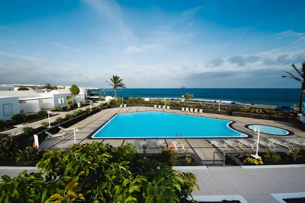 a pool with chairs and the ocean in the background at Bungalow 10 - Caleta Campos in Arrieta