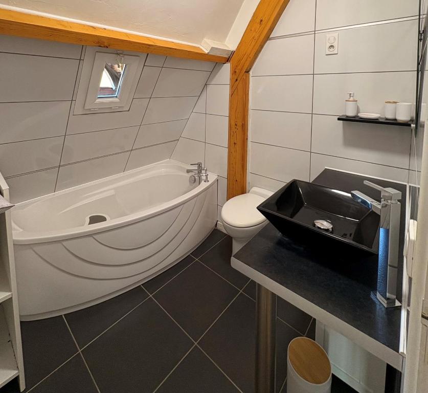 a bathroom with a tub and a toilet and a sink at Maison spacieuse - Jacuzzi - Proche cœur historique in Sarlat-la-Canéda