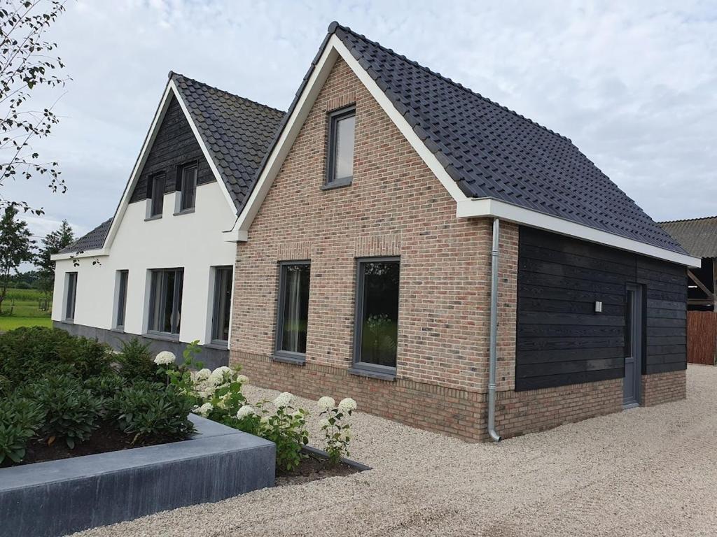 a brick house with a large garage at Compleet nieuw vakantiehuis Villa de Berken in Ede