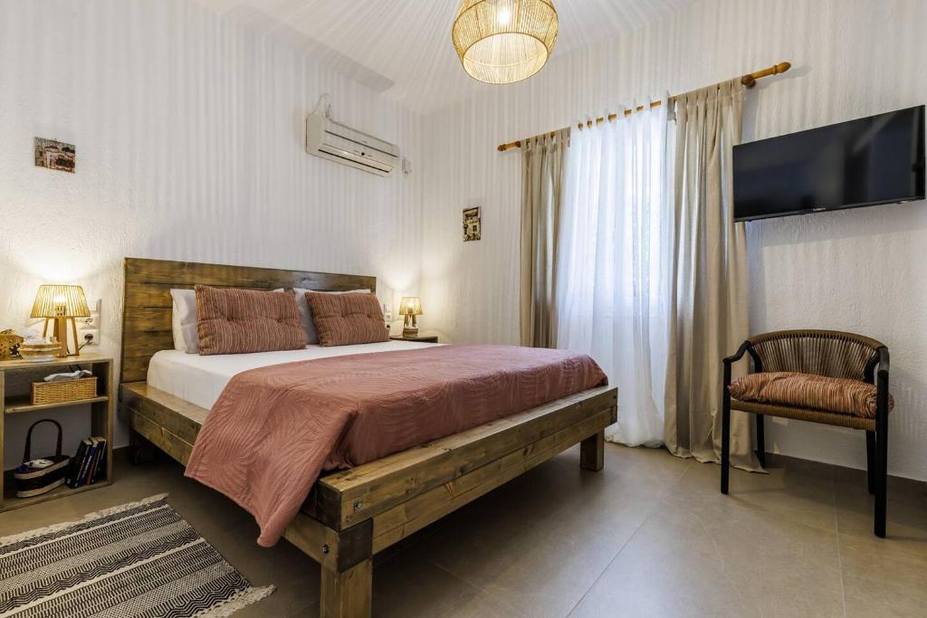 a bedroom with a large bed and a chair at Wood in White in Panormos Skopelos