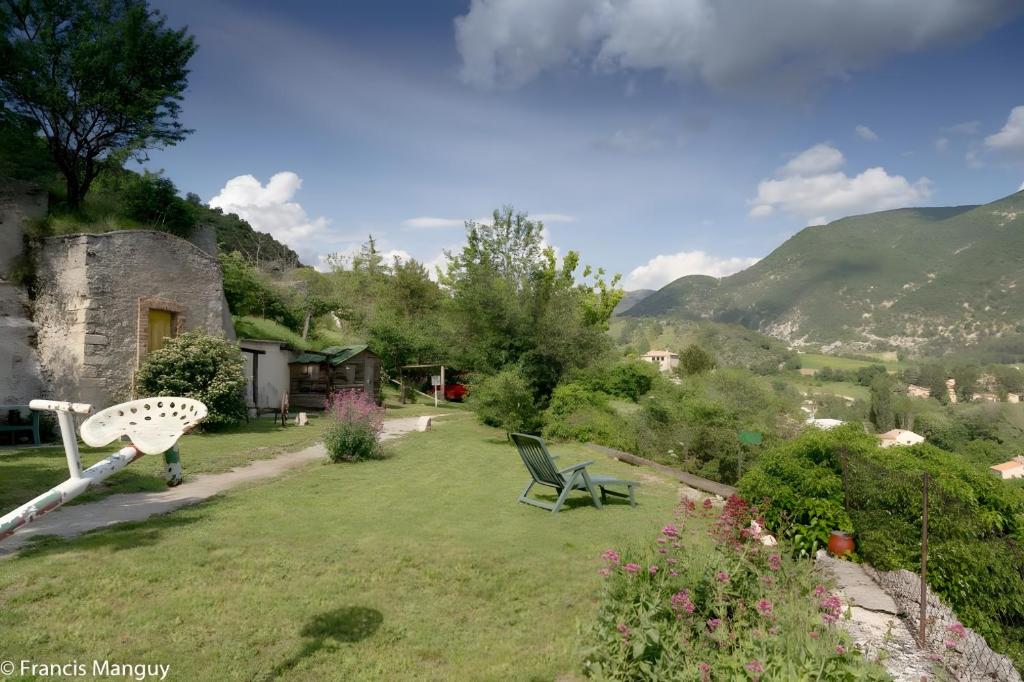 a garden with a chair and a house and mountains at Chambres D'hôtes Le Bellevue - in Montbrun-les-Bains