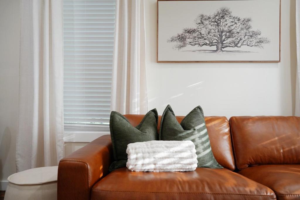 ein braunes Ledersofa mit Kissen drauf in der Unterkunft Oak and Agave House - Downtown New Braunfels Retreat in New Braunfels