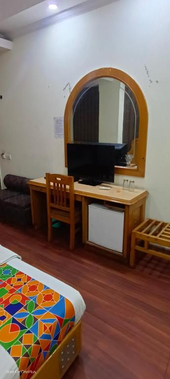 Una habitación con un escritorio, un espejo y una cama. en Kochar con by guruji hospitality, en Nueva Delhi