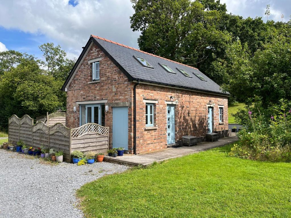 ein kleines Backsteinhaus mit einer Veranda und Fenstern in der Unterkunft Maes Y Grove Cottage in Llanddarog