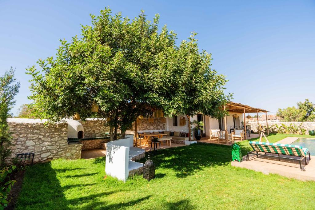a garden with a tree and a table and bench at Villa Yakout in Ghazoua