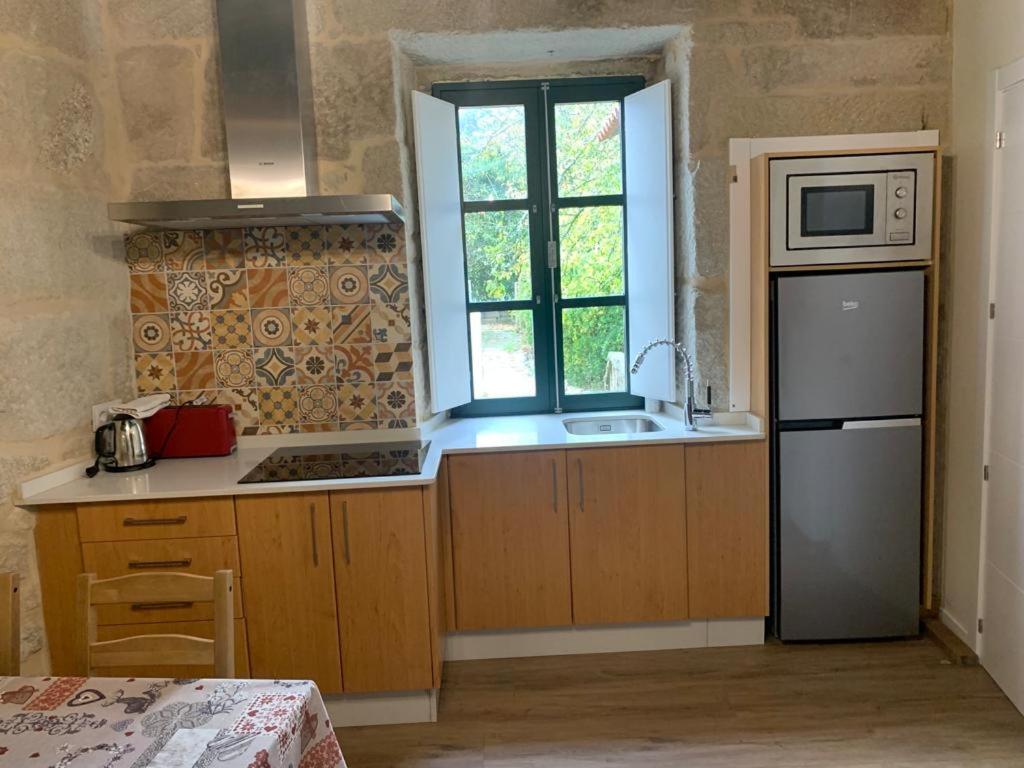 a kitchen with a sink and a refrigerator and a window at Noelmar II Combarro in Combarro