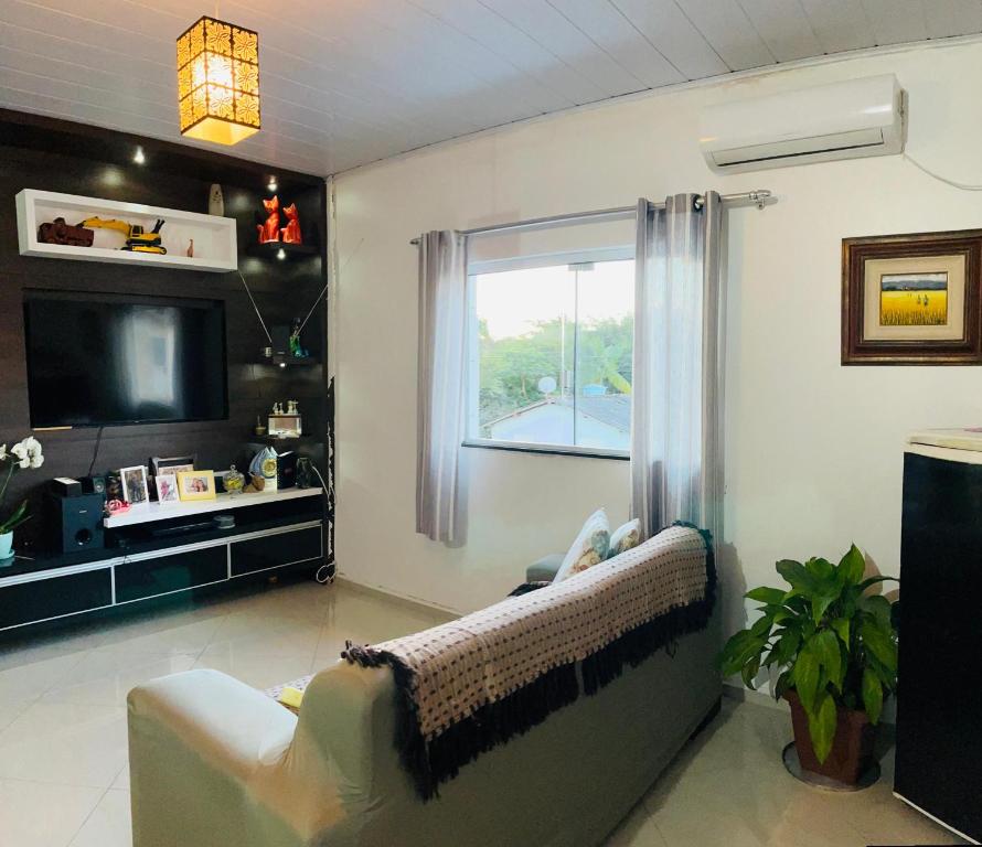 a living room with a couch and a television at Casa próximo à praia Canasvieiras e ingleses in Florianópolis