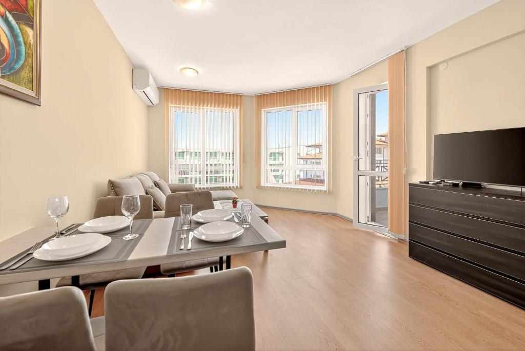 Una sala de estar con una mesa de comedor y un televisor. en Апартамент Danili нов двустаен апартамент с басейн и паркомясто в гр Бяла, en Byala