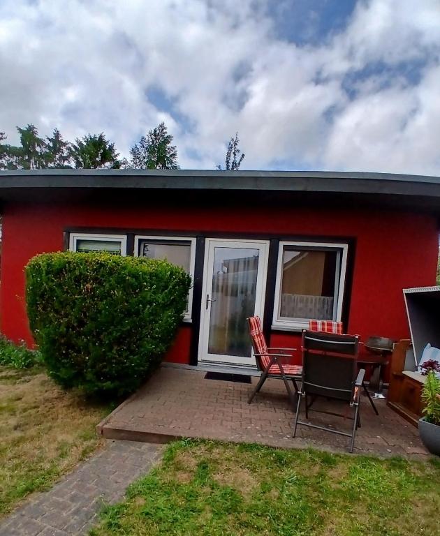 a red house with a table and chairs in front of it at Ferienbungalow in Zirkow