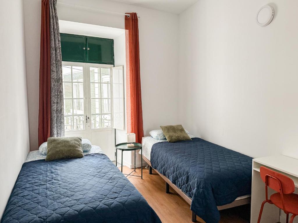 a bedroom with two beds and a window at Sao Pedro Guest House in Faro
