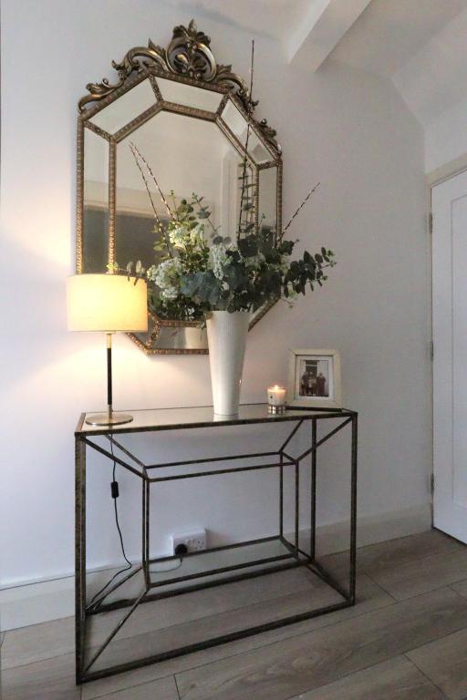 a console table with a mirror and a vase with flowers at No 26 Town House in Killarney