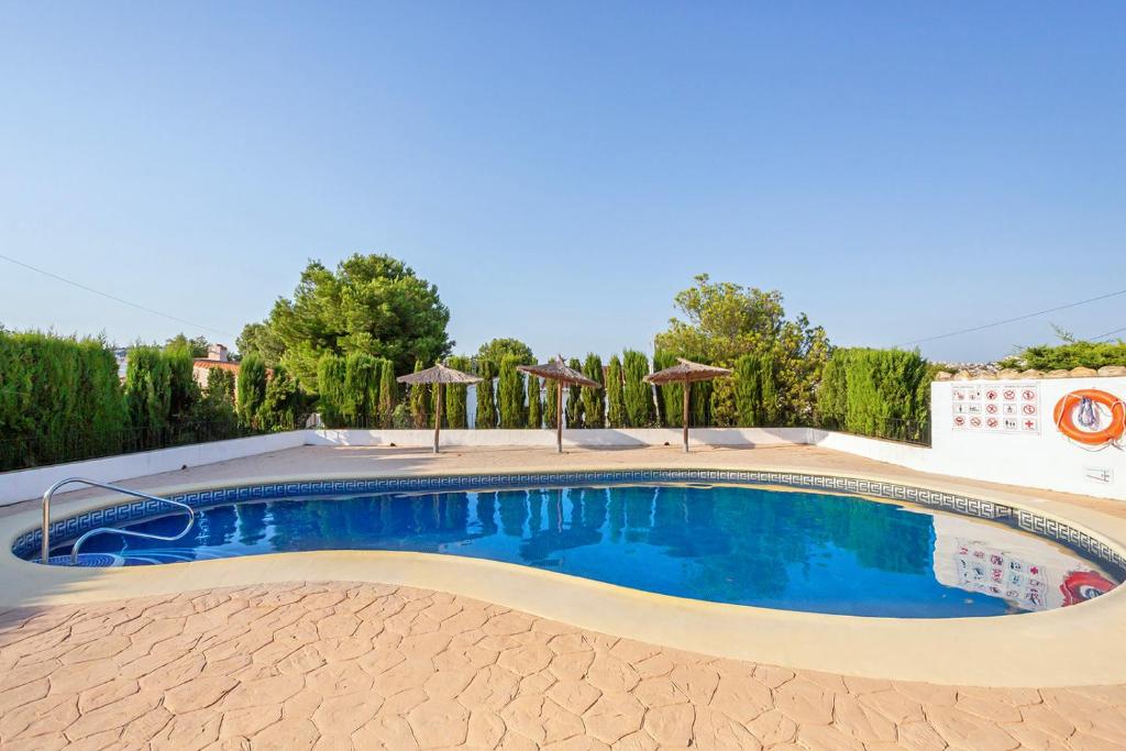 a swimming pool with blue water and umbrellas at Moraira Sweet Home with AC in Teulada