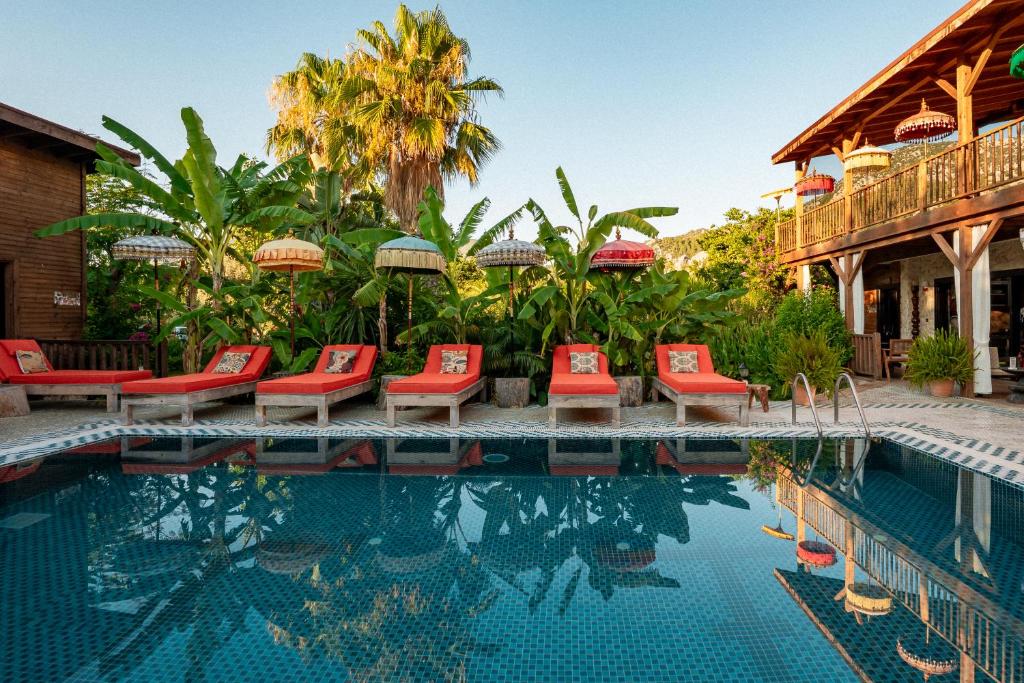 a pool at a resort with chairs and umbrellas at Naturelife Bungalows & SPA in Cıralı
