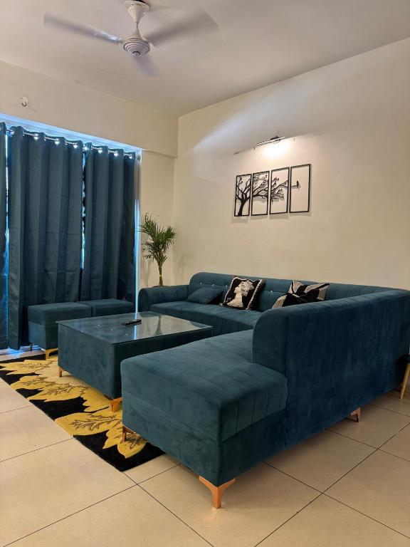 a living room with two blue couches and a table at 3BHK Cozy Apartment in Zirakpur