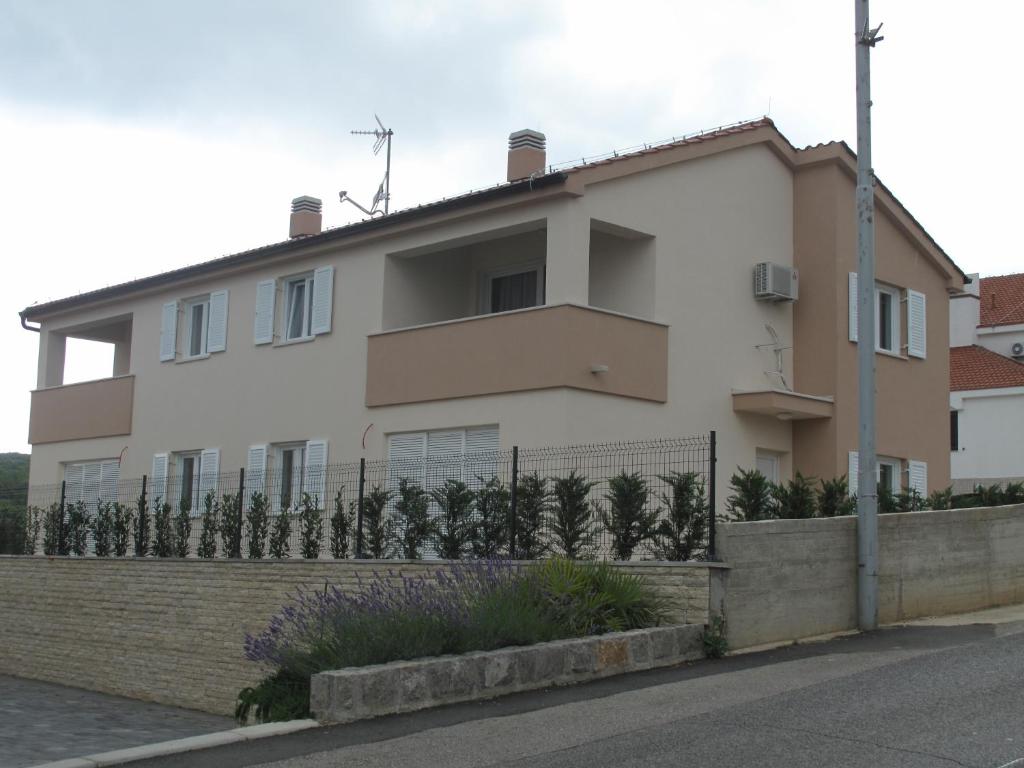 a white house with a fence in front of it at Apartments Mia Krk in Krk