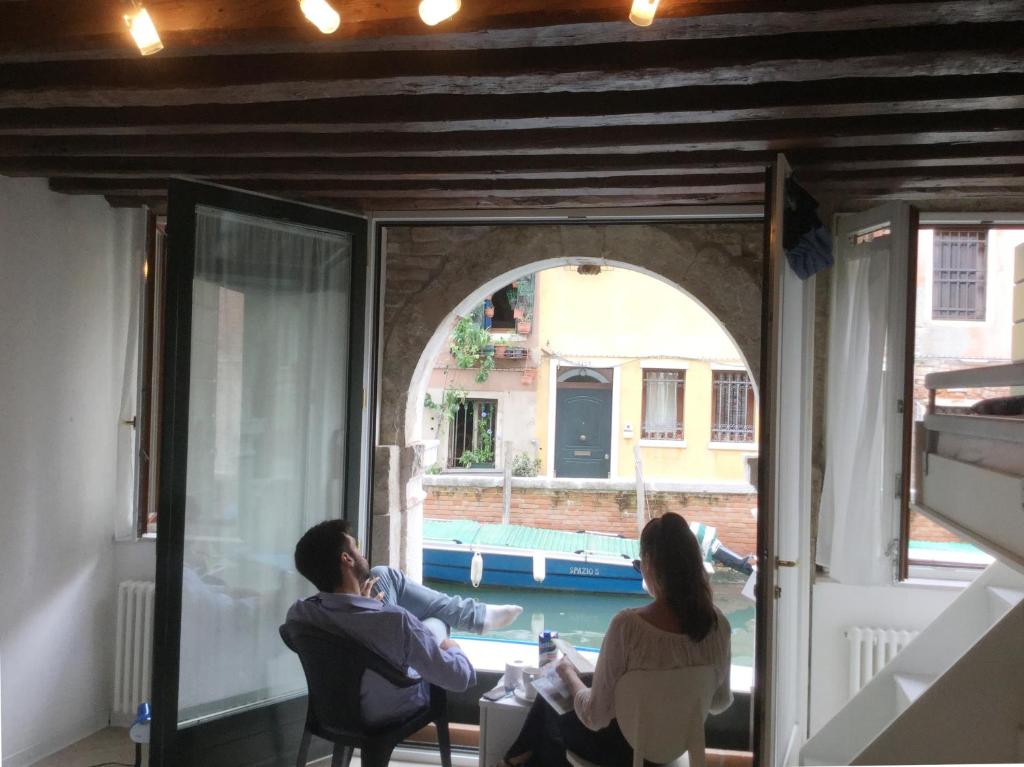 un hombre y una mujer sentados en una mesa en un balcón en La Coccola en Venecia