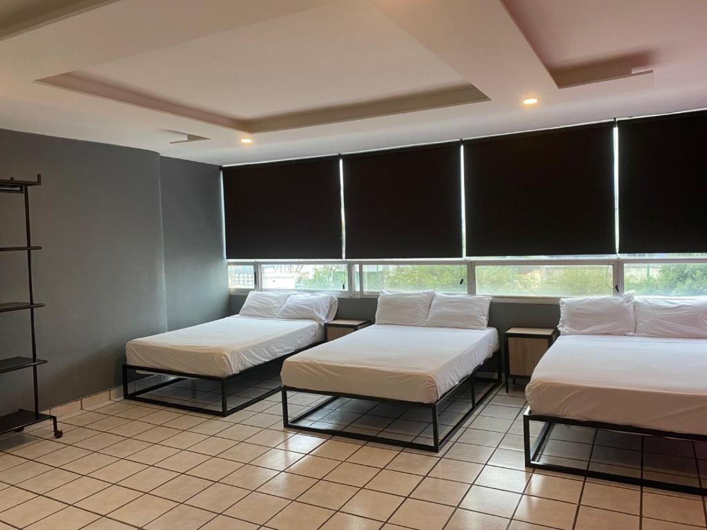 a room with three beds and two windows at Unidades Privadas con AC-TV-WiFi y Estacionamiento en Centro de MTY in Monterrey