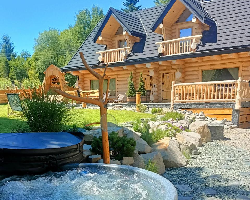 a log cabin with a fountain in front of a house at Bale na Skale Chata & SPA-Zawoja in Skawica