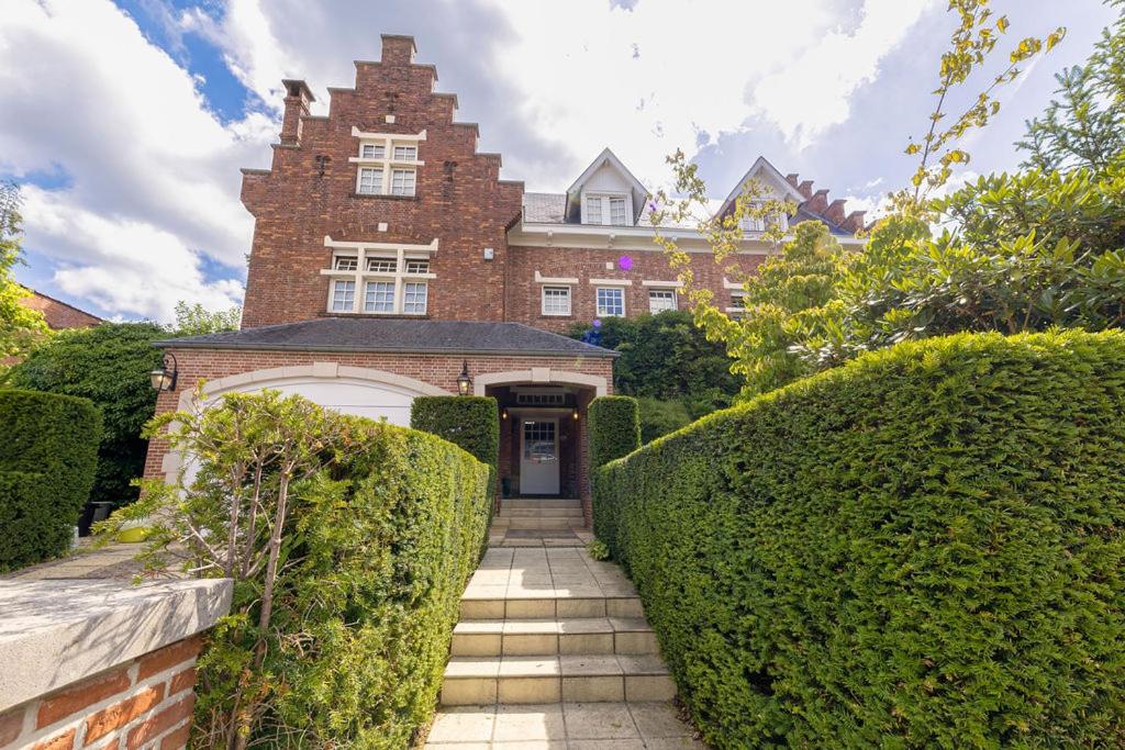 a brick house with a gate and bushes at The Castle in Brussels